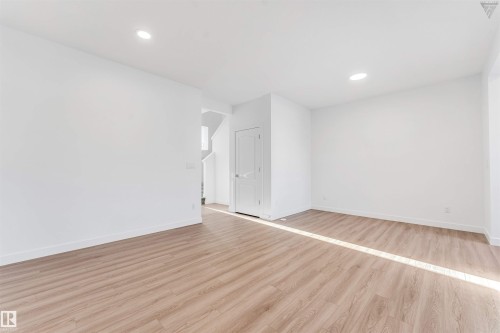 Spacious room with wood-finish flooring, recessed lighting, white baseboards, and a solid white door - 1224 14 Avenue Nw, Edmonton, AB - Indoor Photo Showing Other Room