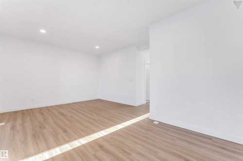 Spacious interior room featuring light wood-finish flooring, recessed lighting, white walls, and white baseboards - 1224 14 Avenue Nw, Edmonton, AB - Indoor Photo Showing Other Room