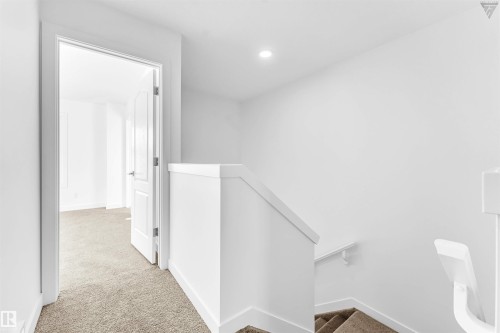 Carpeted hallway featuring a recessed light, a white paneled door, a staircase with a white railing, and a white handrail - 1224 14 Avenue Nw, Edmonton, AB - Indoor Photo Showing Other Room