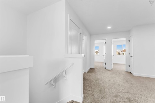 Upper-level landing featuring neutral carpeting, white walls, recessed lighting, and multiple doorways leading to additional rooms - 1224 14 Avenue Nw, Edmonton, AB - Indoor Photo Showing Other Room