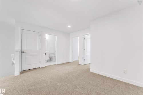 Carpeted interior area featuring white walls, white trim, and white two-panel interior doors - 1224 14 Avenue Nw, Edmonton, AB - Indoor Photo Showing Other Room