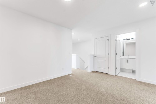 Neutral-toned carpeting extends throughout this interior space, complemented by crisp white walls and ceiling - 1224 14 Avenue Nw, Edmonton, AB - Indoor Photo Showing Other Room
