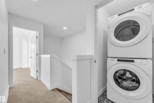Built-in laundry closet with stacked washer and dryer unit, featuring patterned floor tiles - 1224 14 Avenue Nw, Edmonton, AB - Indoor Photo Showing Laundry Room