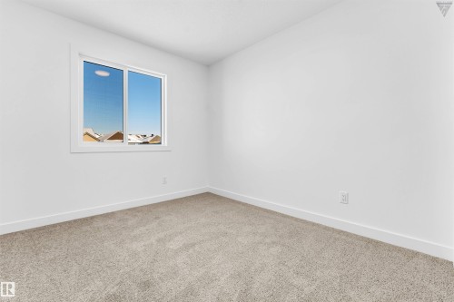 Room featuring a large window with white trim, light-colored carpeting, white baseboards, and neutral wall tones - 1224 14 Avenue Nw, Edmonton, AB - Indoor Photo Showing Other Room