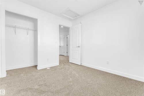Carpeted room featuring a closet with wire shelving, white walls, white trim, and a white interior door - 1224 14 Avenue Nw, Edmonton, AB - Indoor Photo Showing Other Room