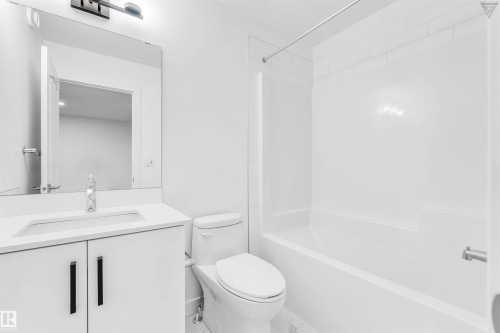 Full bathroom featuring a white vanity with integrated sink, quartz-finish countertop, and matte black hardware - 1224 14 Avenue Nw, Edmonton, AB - Indoor Photo Showing Bathroom