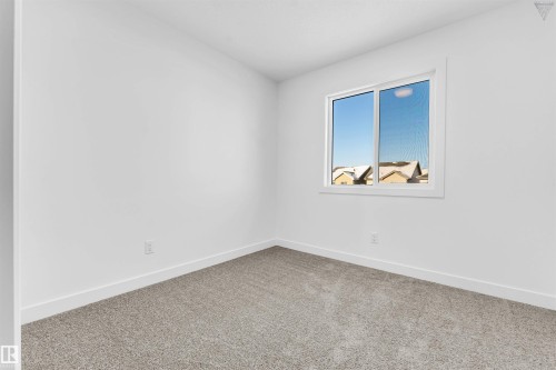 Light-filled room featuring a large window, neutral carpeting, white walls, and bright baseboards - 1224 14 Avenue Nw, Edmonton, AB - Indoor Photo Showing Other Room