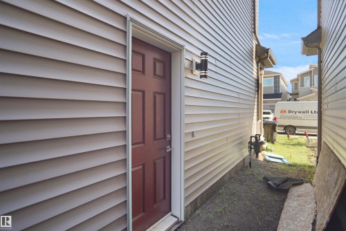 Exterior entrance featuring a rich mahogany-toned door set within light-toned horizontal siding - 1224 14 Avenue Nw, Edmonton, AB - Outdoor With Exterior