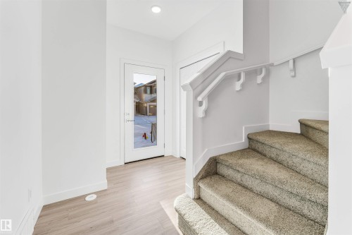 Entryway with wood-finish flooring, a full-lite door, and a staircase featuring carpeted steps and a white handrail - 1224 14 Avenue Nw, Edmonton, AB - Indoor Photo Showing Other Room