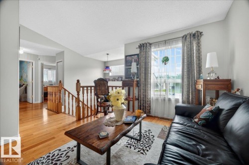 Hardwood flooring extends through the living area and hallway, complemented by light gray wall paint and white trim - 5108 138A Avenue, Edmonton, AB 