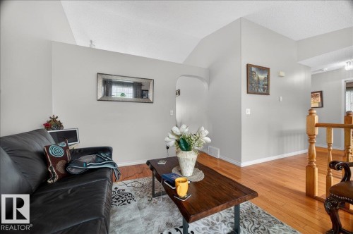 Living area featuring light gray walls, wood-finish flooring, and a vaulted ceiling - 5108 138A Avenue, Edmonton, AB 
