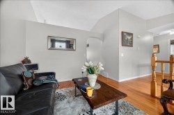 Living area featuring light gray walls, wood-finish flooring, and a vaulted ceiling - 
