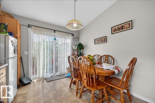 Tiled flooring in a dining area featuring a sliding glass door, a semi-flush mount light fixture, and light gray wall paint - 5108 138A Avenue, Edmonton, AB 