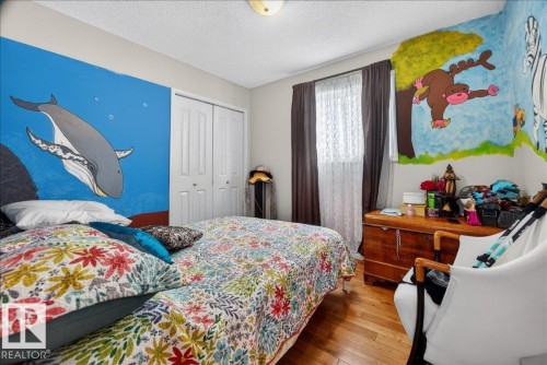 Bedroom featuring wood-finish flooring, a double-door closet, and a ceiling-mounted light fixture - 5108 138A Avenue, Edmonton, AB 