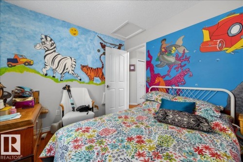 Room featuring vibrant wall murals, a ceiling access panel, and a white interior door - 5108 138A Avenue, Edmonton, AB 