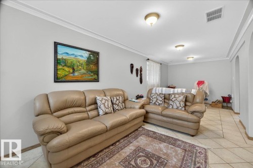 Spacious interior featuring light gray walls, crown molding, ceiling-mounted light fixtures, a window with vertical blinds, and tiled flooring - 5108 138A Avenue, Edmonton, AB 
