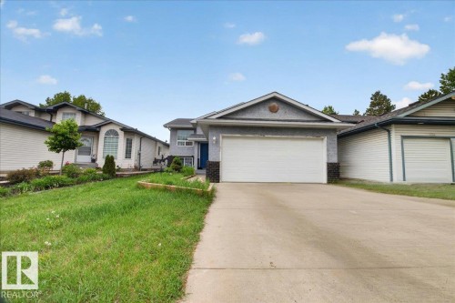 Exterior featuring a concrete driveway, attached garage with a white door, and textured stucco siding - 5108 138A Avenue, Edmonton, AB 