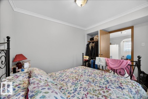 Neutral-toned bedroom with crown molding, featuring a built-in closet with an adjacent doorway - 5108 138A Avenue, Edmonton, AB 