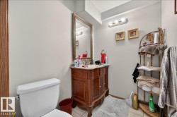 Bathroom featuring a vanity with a carved wood-finish base, a decorative framed mirror, and a white toilet - 
