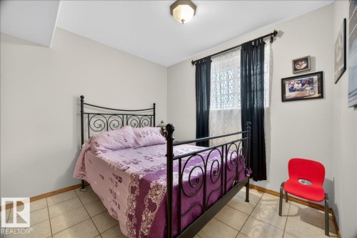Room featuring neutral wall tones, ceramic tile flooring, and a window with security bars - 5108 138A Avenue, Edmonton, AB 