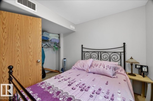 Bedroom featuring a wood-finish door, light gray painted walls, and an open closet space - 5108 138A Avenue, Edmonton, AB 