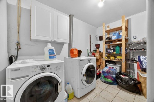 Dedicated laundry area featuring tile flooring, white wall-mounted cabinetry, and ample shelving for organization - 5108 138A Avenue, Edmonton, AB 