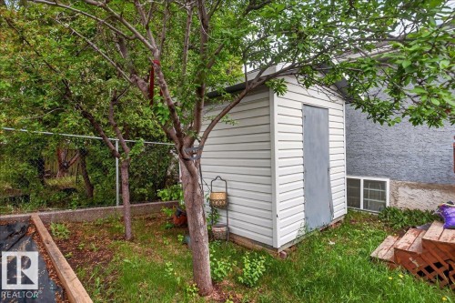 Detached shed featuring horizontal siding and a solid door, surrounded by mature trees - 5108 138A Avenue, Edmonton, AB 