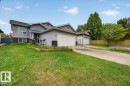 Stucco exterior featuring multiple garages, a blue entry door, and varied rooflines - 5108 138A Avenue, Edmonton, AB 