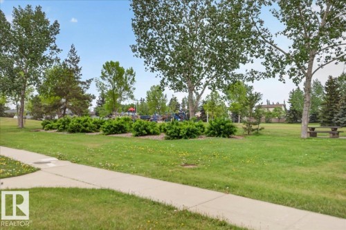 Expansive green space featuring mature trees, manicured lawns, and a concrete pathway - 5108 138A Avenue, Edmonton, AB 