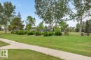Expansive green space featuring mature trees, manicured lawns, and a concrete pathway - 5108 138A Avenue, Edmonton, AB 