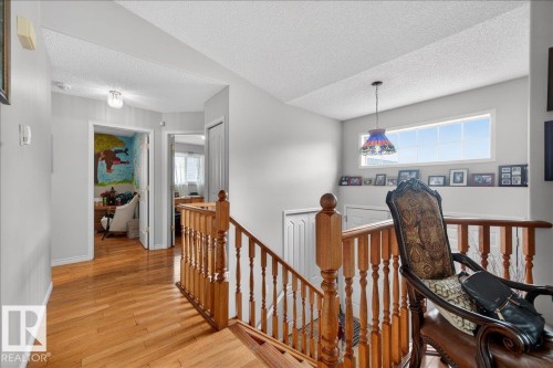 Hardwood flooring extending throughout, featuring a natural wood staircase with wood balusters and newel posts - 5108 138A Avenue, Edmonton, AB 