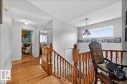 Hardwood flooring extending throughout, featuring a natural wood staircase with wood balusters and newel posts - 