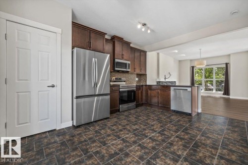 Kitchen featuring dark wood cabinetry, stainless steel appliances, and a tiled backsplash - 356 Pioneer Road, Spruce Grove, AB 