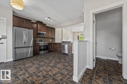 Kitchen featuring dark wood cabinetry, stainless steel appliances, and a mosaic tile backsplash - 