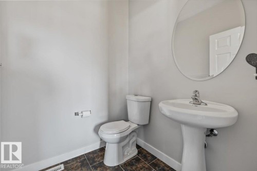Pedestal sink with chrome faucet and circular mirror - 356 Pioneer Road, Spruce Grove, AB 