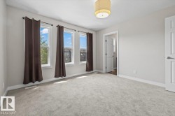 Spacious room featuring light gray carpet flooring, three large windows, a neutral wall color, white trim, and a modern drum light fixture - 