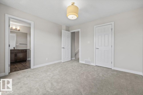Spacious carpeted room featuring a ceiling-mounted light fixture, white trim, and light gray walls - 356 Pioneer Road, Spruce Grove, AB 