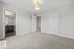 Spacious carpeted room featuring a ceiling-mounted light fixture, white trim, and light gray walls - 