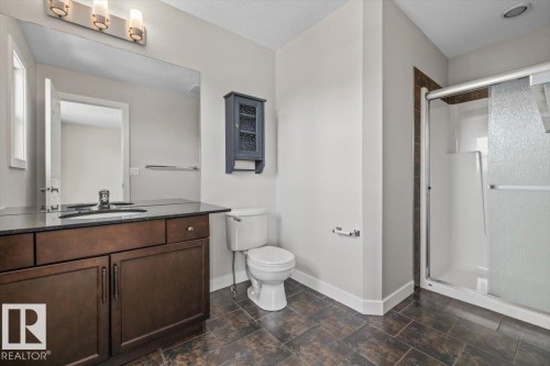 Bathroom featuring a dark wood-finish vanity with a dark countertop, an integrated sink, and a large wall-mounted mirror - 356 Pioneer Road, Spruce Grove, AB 