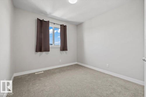 Neutral gray wall finish, plush gray carpeting, white trim, and a window with brown drapes - 356 Pioneer Road, Spruce Grove, AB 