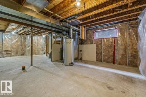 Unfinished basement featuring exposed wood joists, concrete flooring, insulated walls partially covered with plastic sheeting, and a small horizontal window with blinds - 356 Pioneer Road, Spruce Grove, AB 
