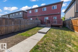 Rear exterior featuring a wood deck with stairs, a concrete pathway, and a fully fenced yard with wood panel fencing - 