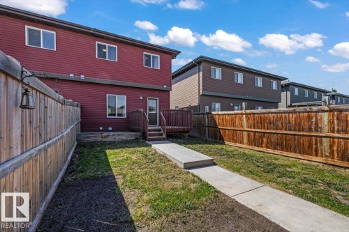 Red siding exterior with multiple windows, a rear deck, and a privacy fence - 356 Pioneer Road, Spruce Grove, AB 