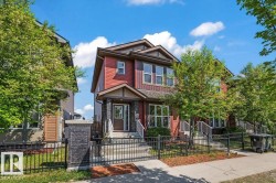 Two-story residence featuring red siding and dark stone facade accents - 