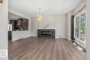 Spacious living area featuring wood-finish flooring, a stone-clad fireplace with an electric insert, and a large multi-pane window - 356 Pioneer Road, Spruce Grove, AB 