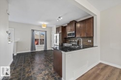 Kitchen area featuring dark wood-finish cabinetry, a black stone countertop, and a mosaic tile backsplash - 