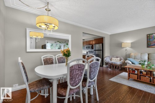 Open-concept dining area featuring wood-finish flooring, crown molding, and a decorative chandelier - 9815 68 Avenue, Edmonton, AB - Indoor Photo Showing Dining Room