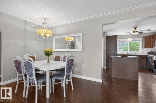 Dining area featuring wood-finish flooring, a decorative chandelier, and crown molding - 9815 68 Avenue, Edmonton, AB - Indoor Photo Showing Dining Room