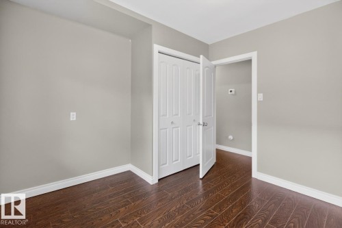Room featuring dark wood-finish flooring, light neutral-toned walls, and white baseboards - 9815 68 Avenue, Edmonton, AB - Indoor Photo Showing Other Room