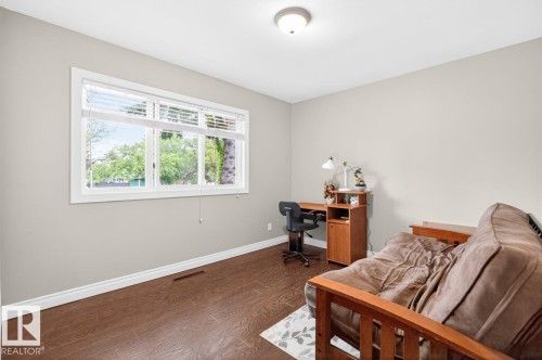 Bright interior space featuring a multi-pane window, neutral wall paint, wood-finish flooring, white baseboards, and a flush-mount ceiling light fixture - 9815 68 Avenue, Edmonton, AB - Indoor